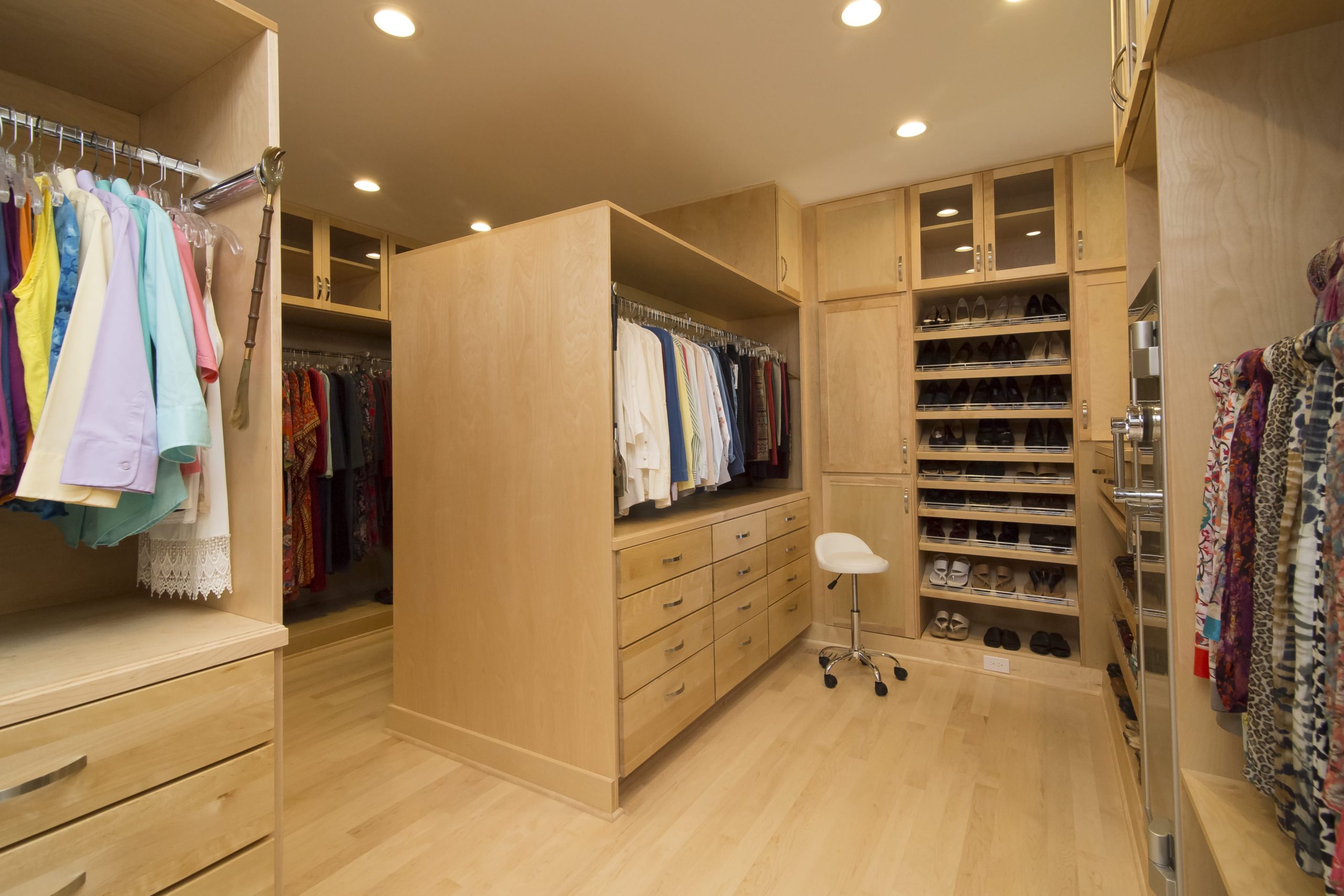 This glamorous primary closet has many different built-in storage options including shoe racks, drawers, cabinets, hanging rods, and cubbies.