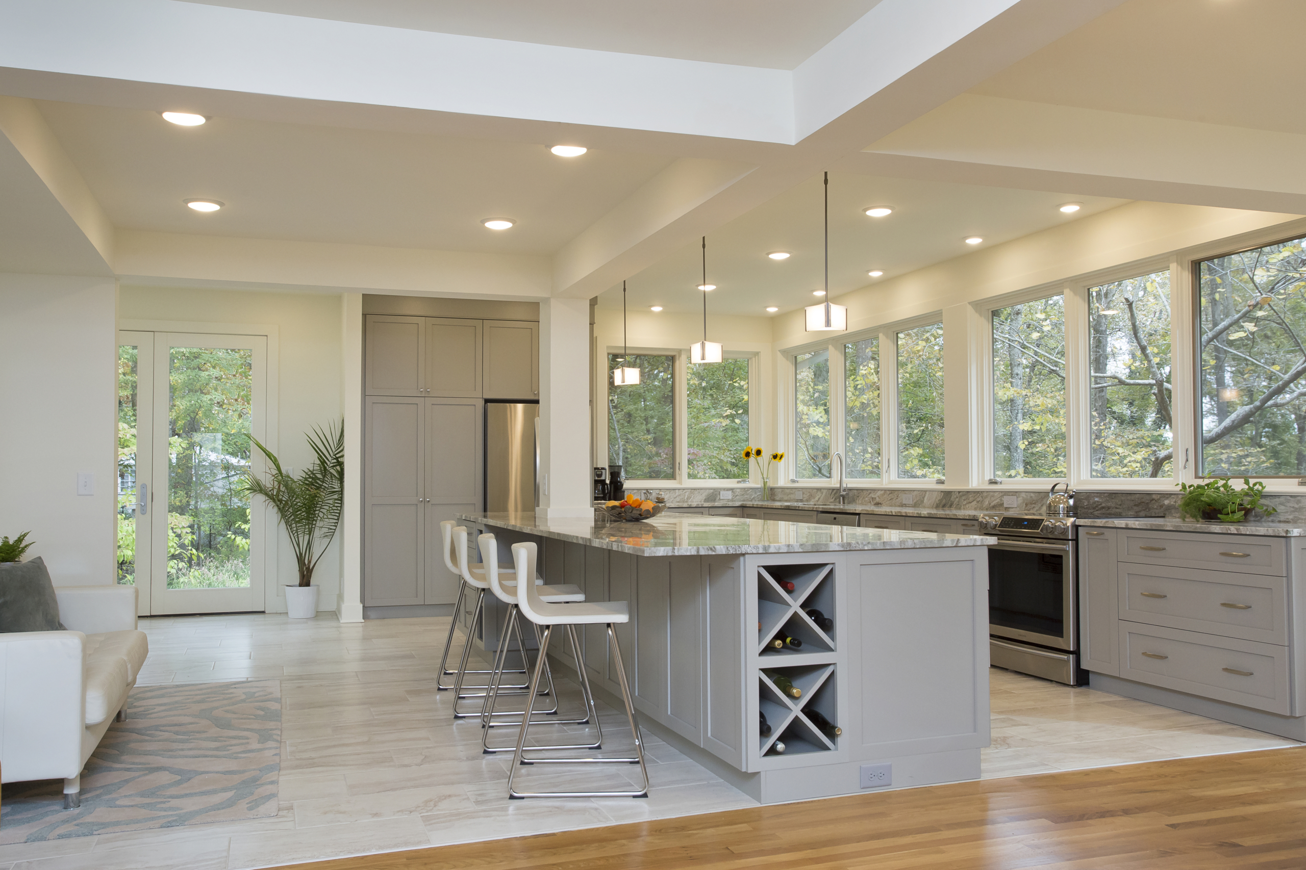 A bright, contemporary and sophisticated kitchen with a large island, generous counter space, built-in wine storage and band of windows overlooking a lush green site
