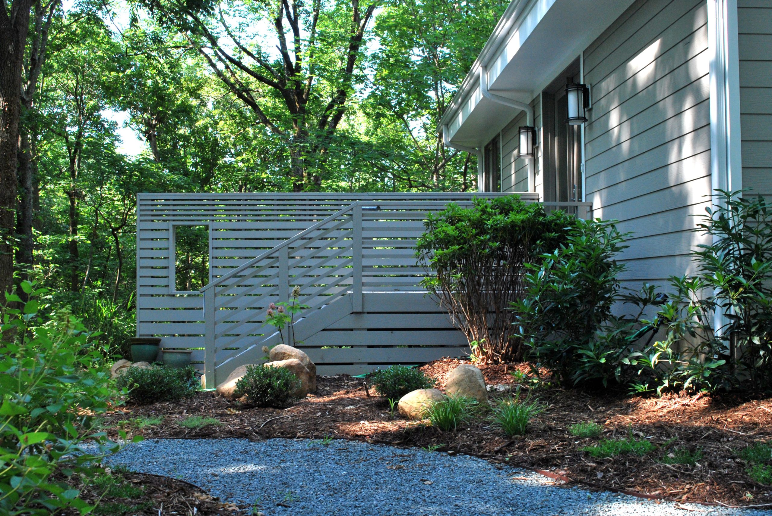 A gravel path through the garden leads to the entry stair and slatted privacy wall, designed to match the rhythm and color of the house's exterior