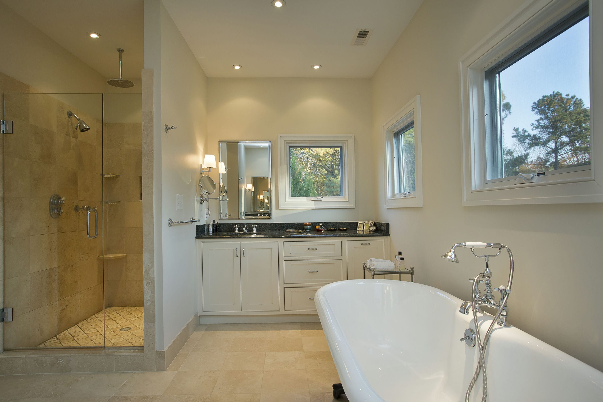 Primary bathroom with spacious shower, clawfoot tub, and separate vanities with inset cabinets