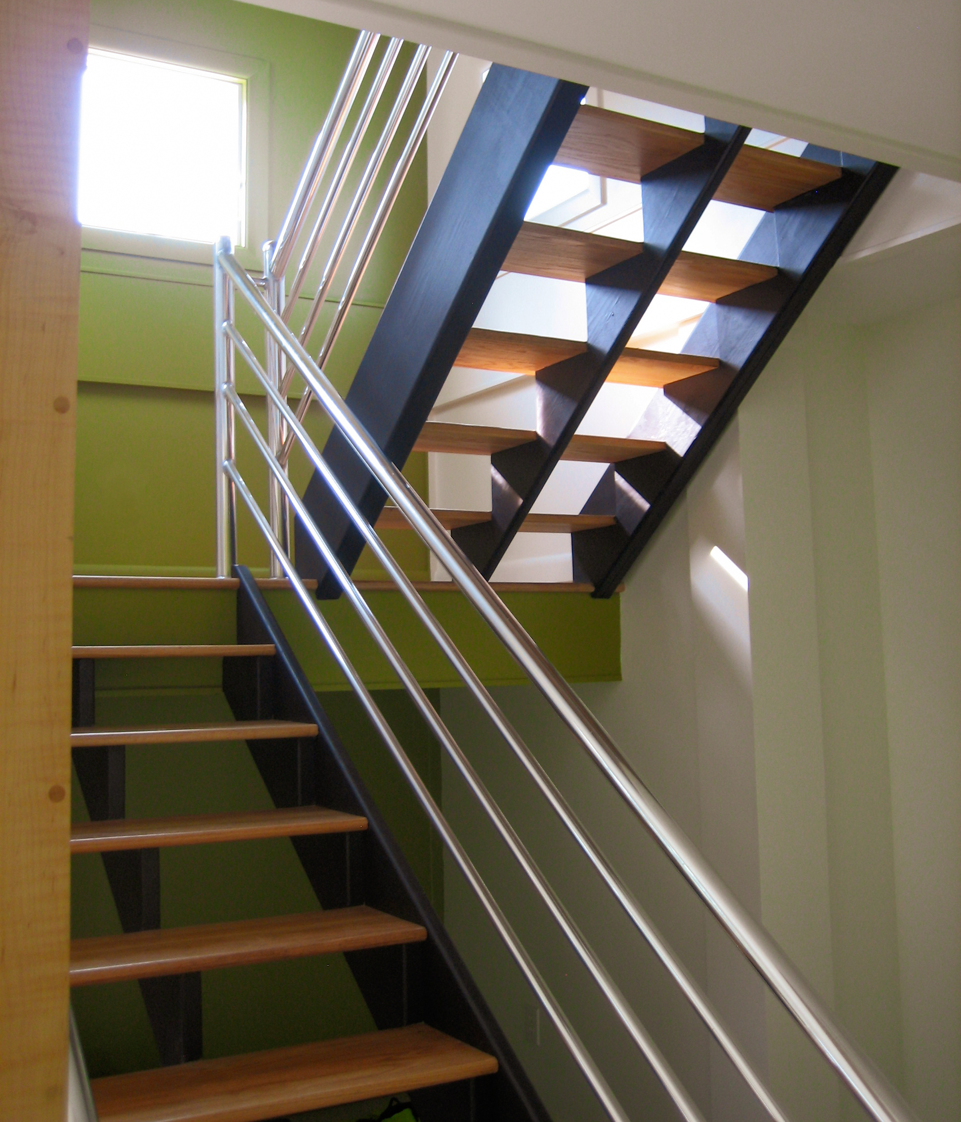 Sleek stairwell with stainless steel railing, chartreuse walls, and open riser stairs