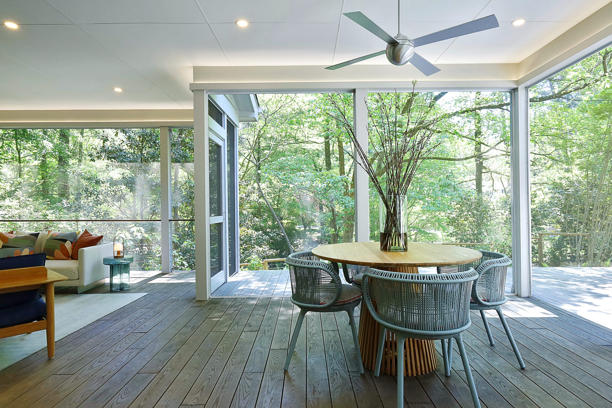 Wood flooring in the porch continues to the open deck past the floor-to-ceiling screens, crating the illusion of an unobstructed connection to the outdoors.