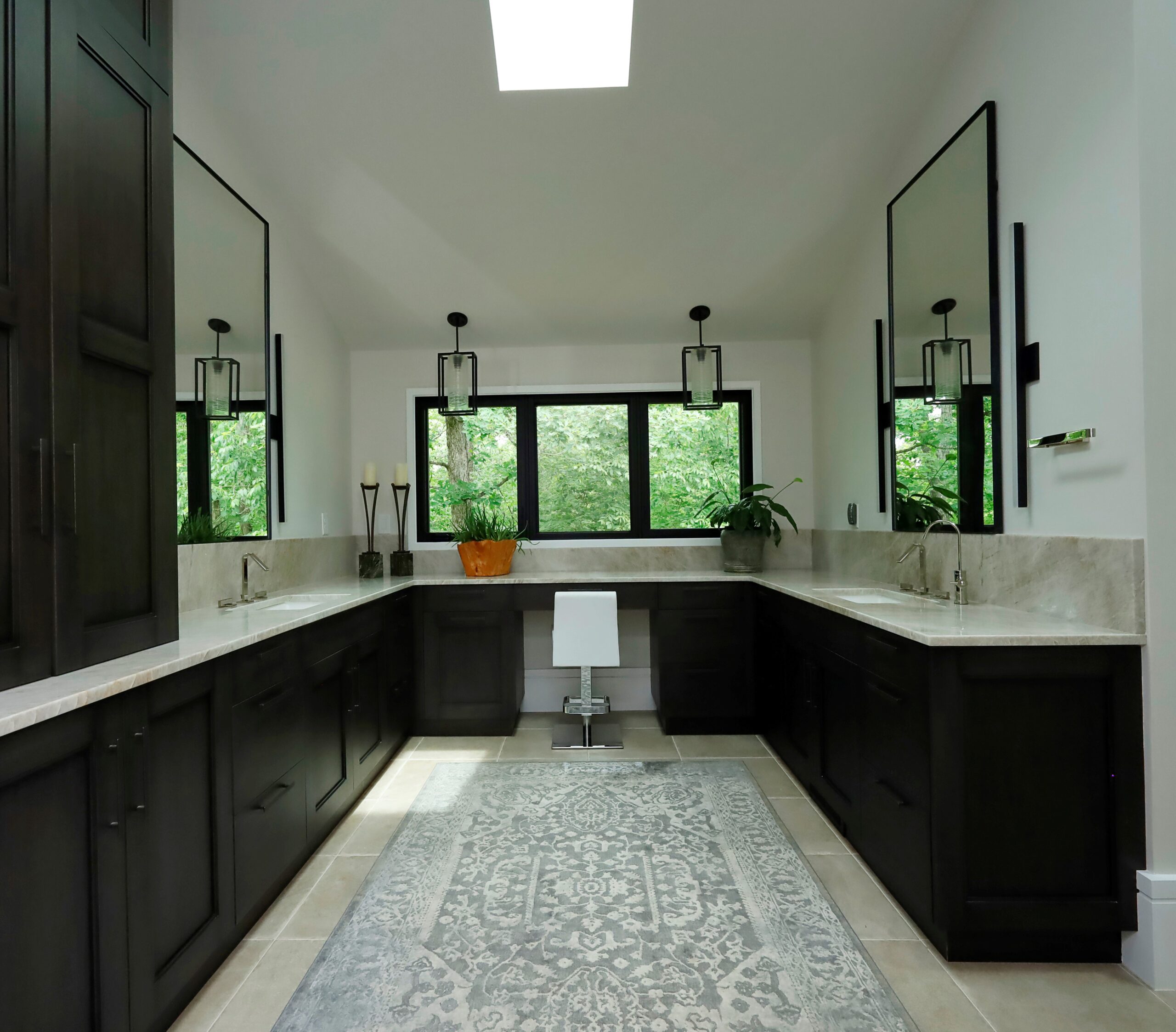 Large windows and skylights illuminate the primary bathroom fitted with double vanities and custom dark wood cabinetry.