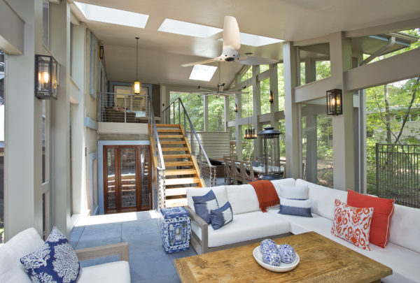 A screen porch with an open wooden stair, large skylights and views into surrounding woods