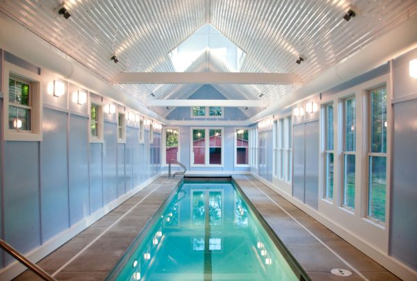 bottom lit indoor lap pool in a bright and airy room with vaulted corrugated metal ceiling