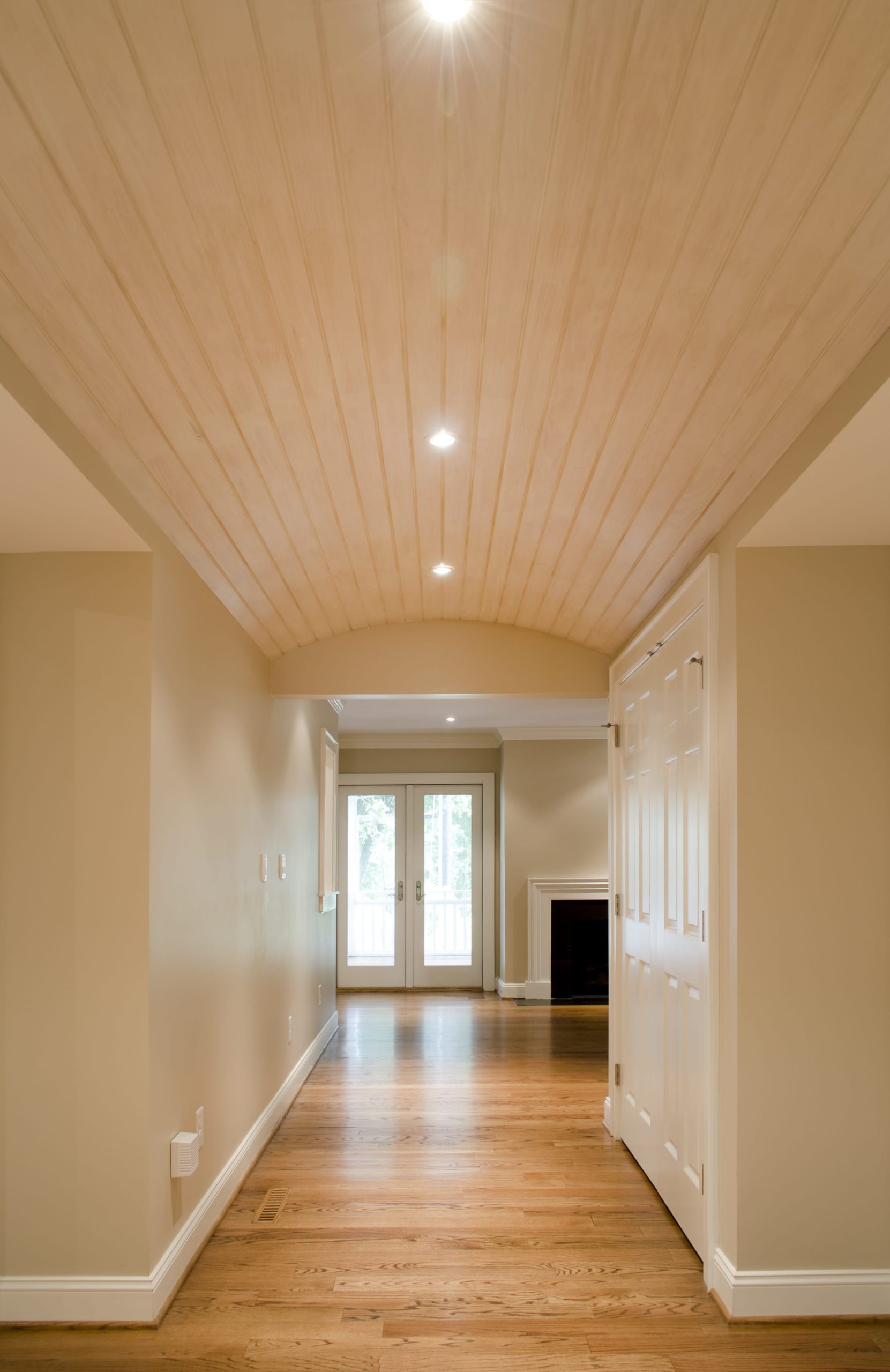 A hallway connecting to the living room has a unique barrel vault ceiling, adding character and charm to the space