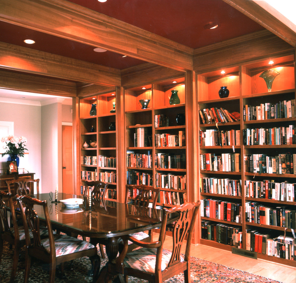 Formal dining space with exposed wood beams and wooden built-in bookshelves lined with books and art.