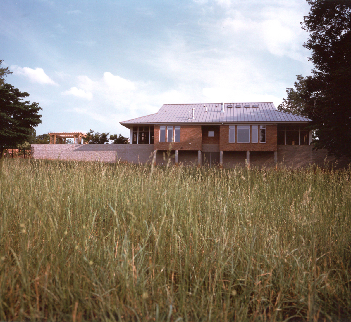 An exterior view of the house shows its grassy surrounding and unique roof form.