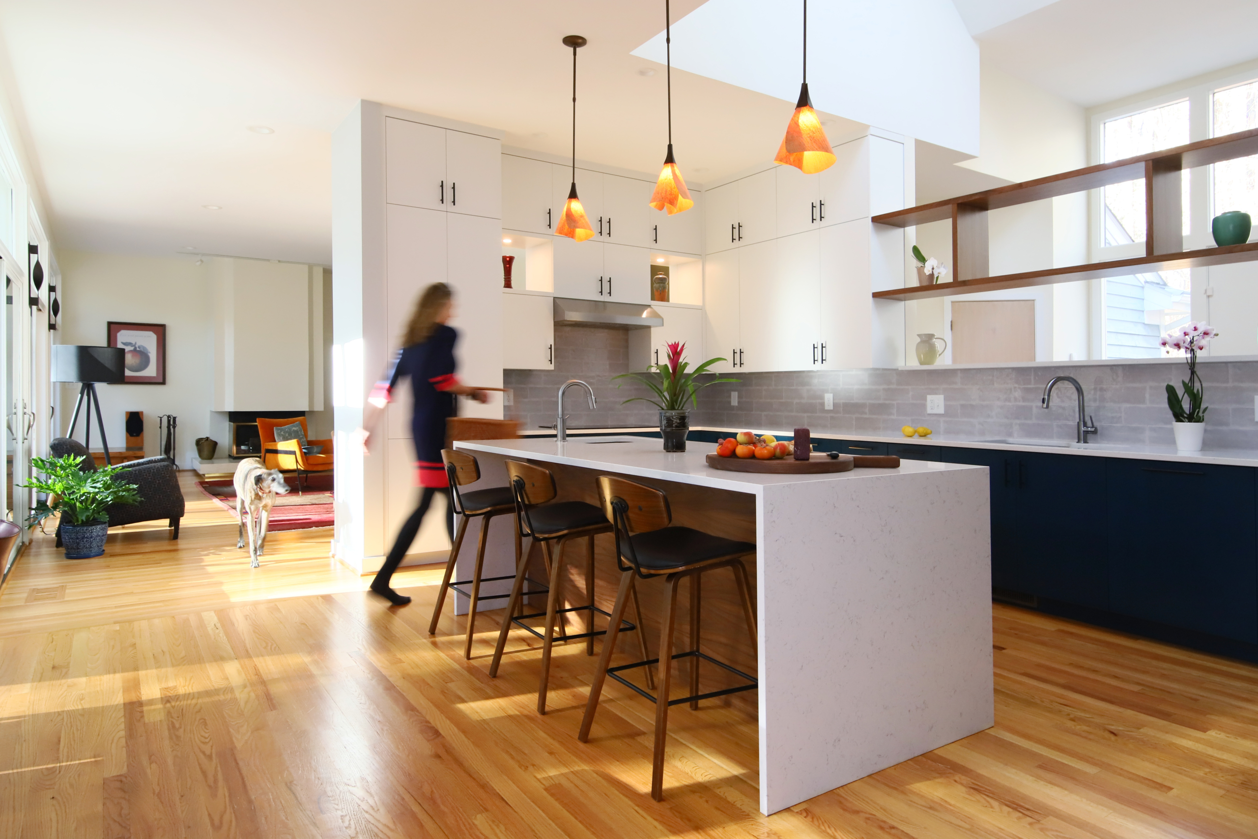 A woman walks through a sleek and contemporary kitchen filled with light