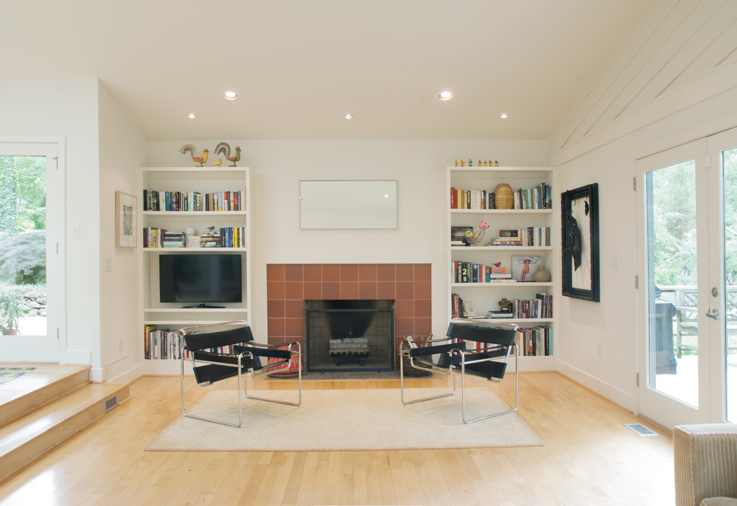 A bright and cozy seating area with built-in bookshelves and a terra cotta tiled fireplace