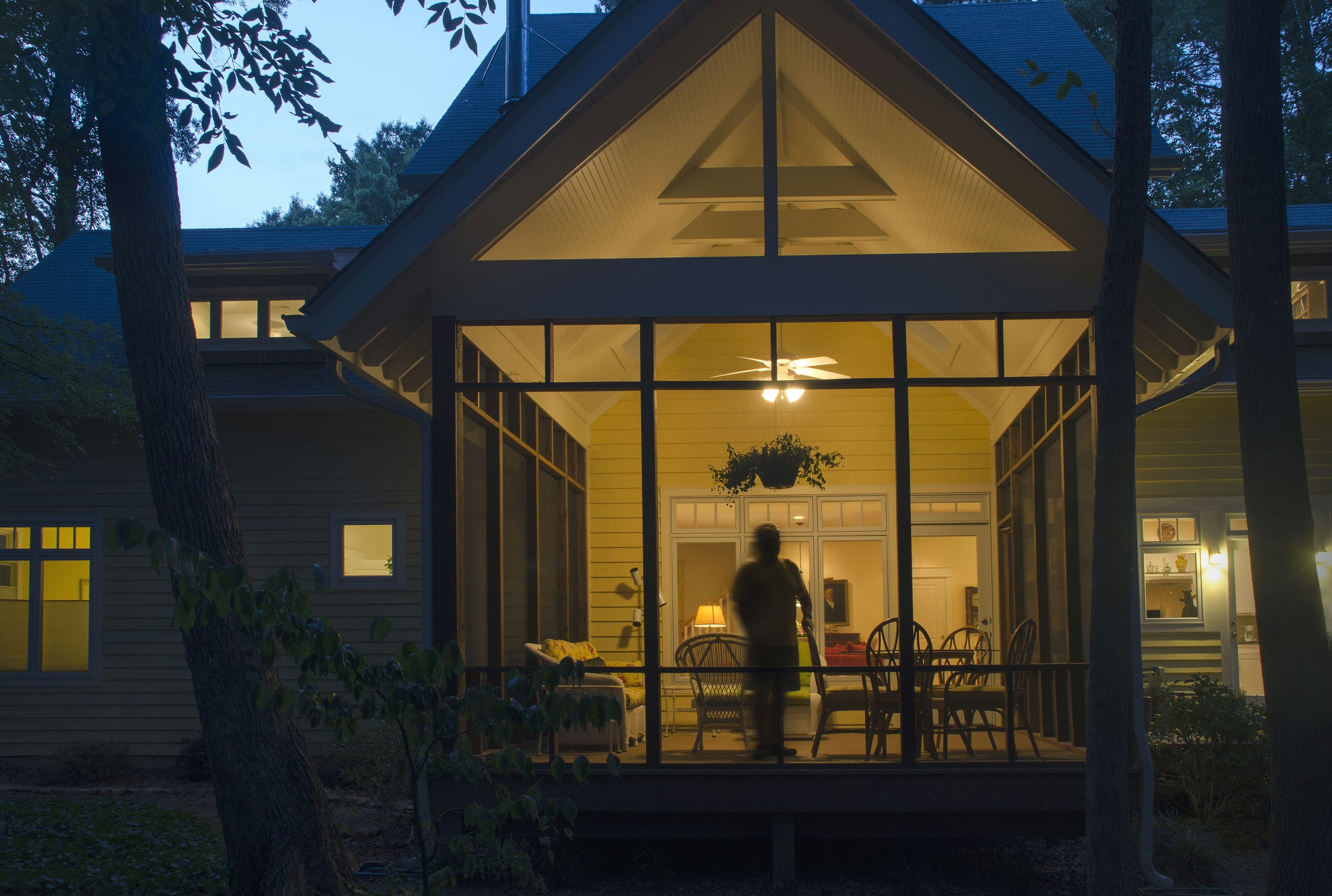 Exterior of screen porch with exposed rafter tails glowing at dusk