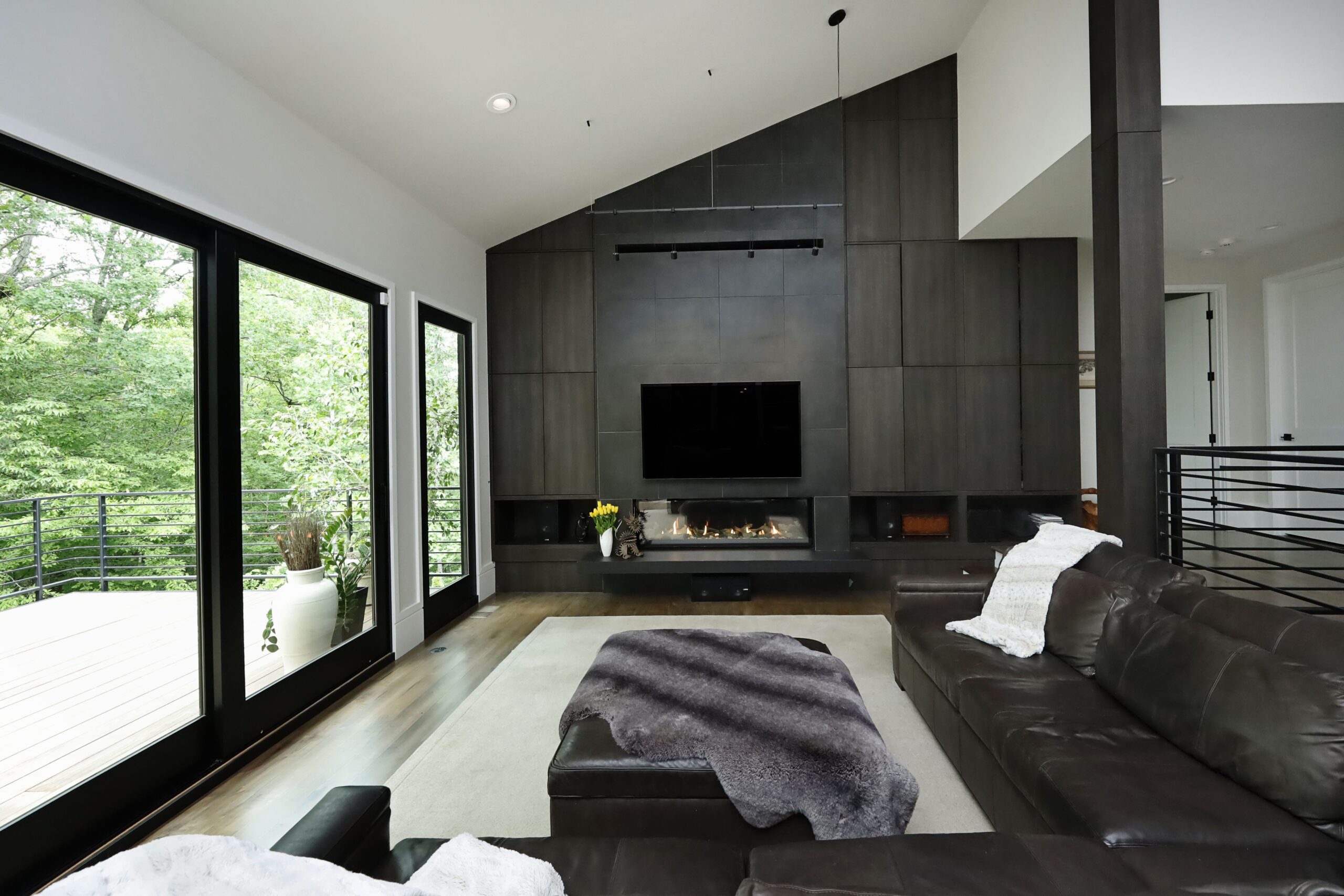 Large sliding doors connect the living room to the deck. Dark wood floor-to-ceiling built-ins with a linear gas fireplace create an elegant and timeless living space.
