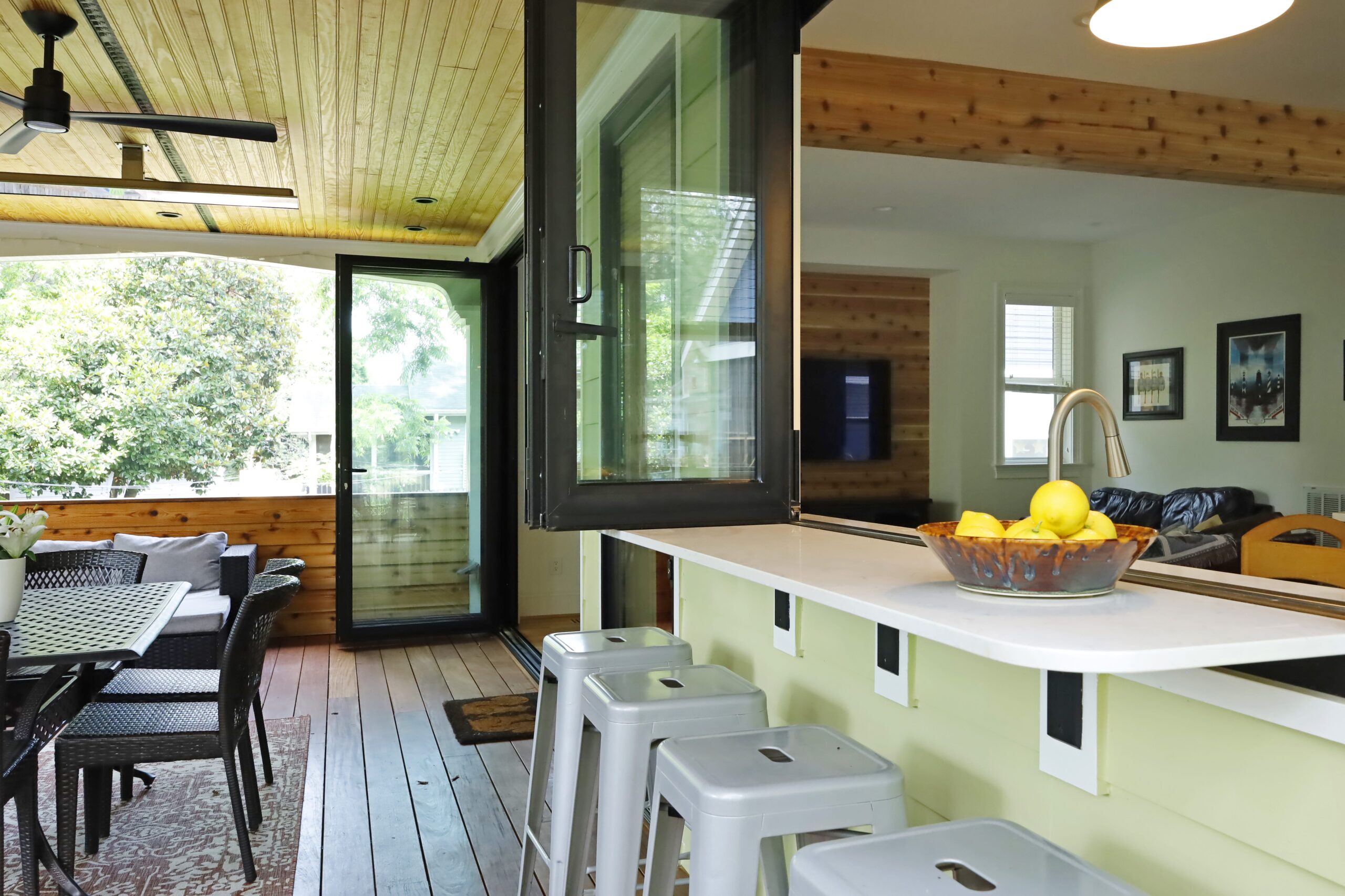Accordion-style windows above the kitchen sink open up to the covered porch with a view overlooking the back yard.
