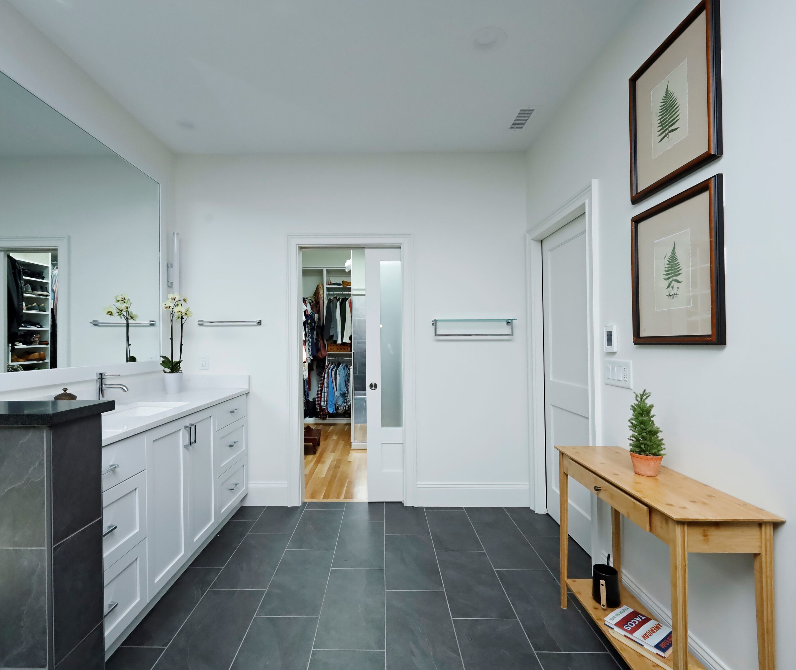 A sleek bathroom with black tile floors connects to a large walk-in closet.