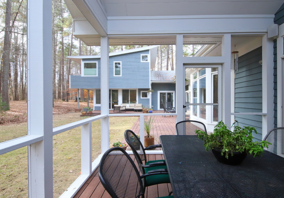 A bright and airy screen porch overlook the existing house, yard and wooded surroundings